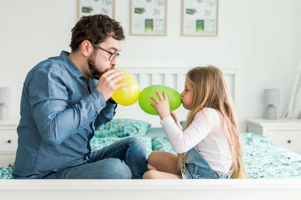 parent and child practicing calming breathing together using balloons
