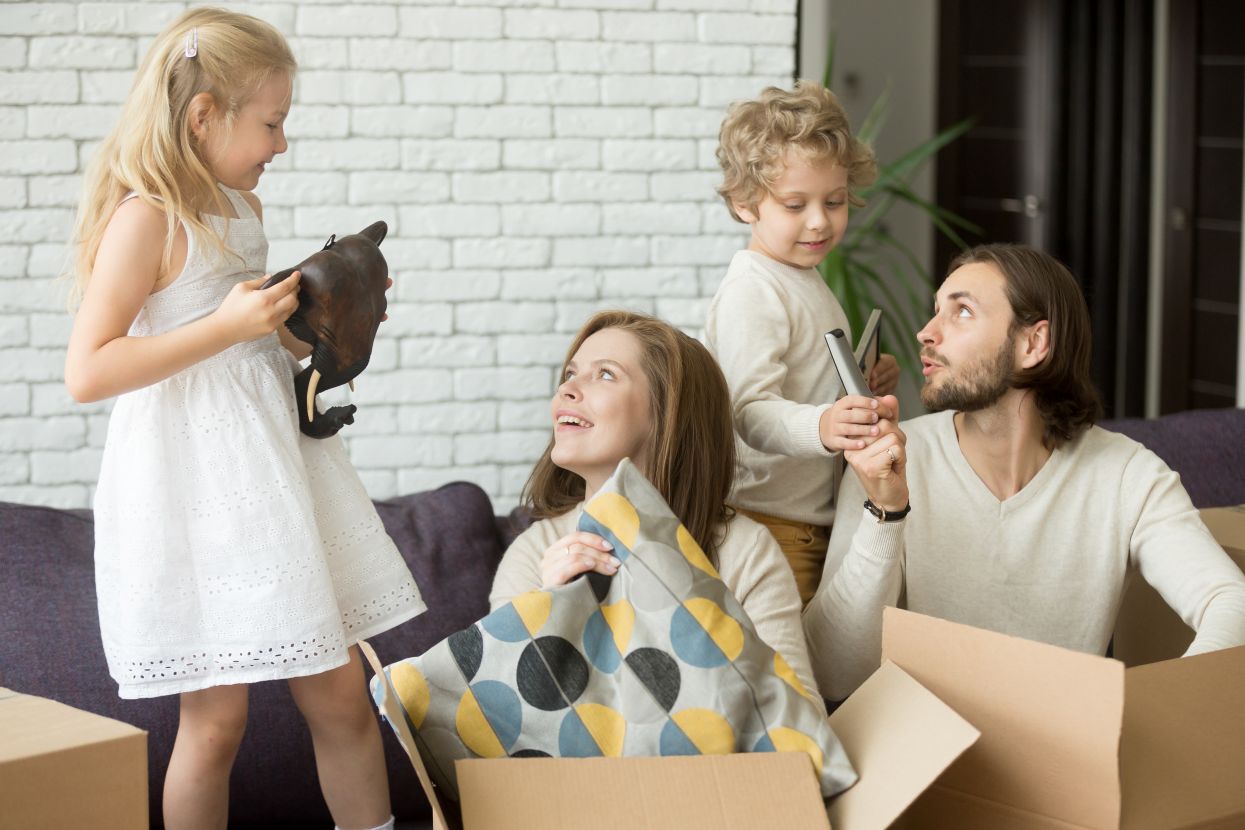 Happy children helping their parents unpack boxes on moving day