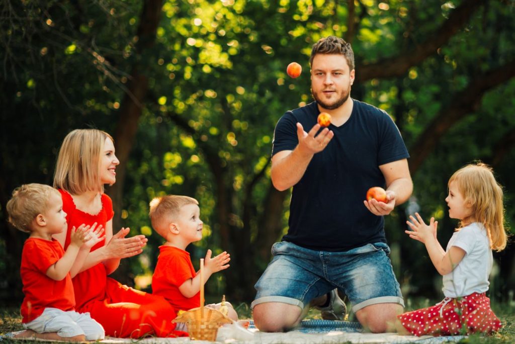 Father juggling oranges in front of his family