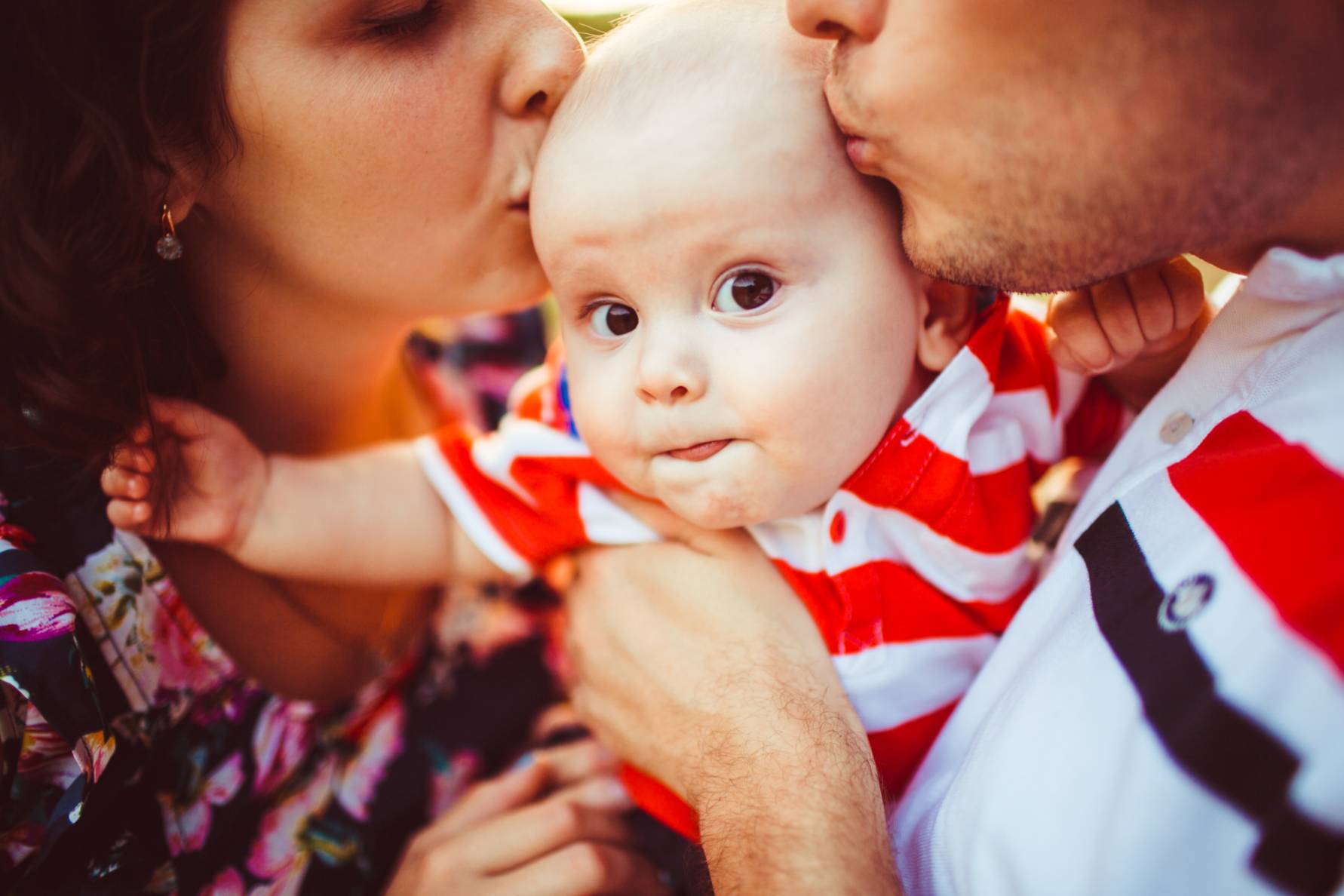 A little boy triying to escape his parents kisses