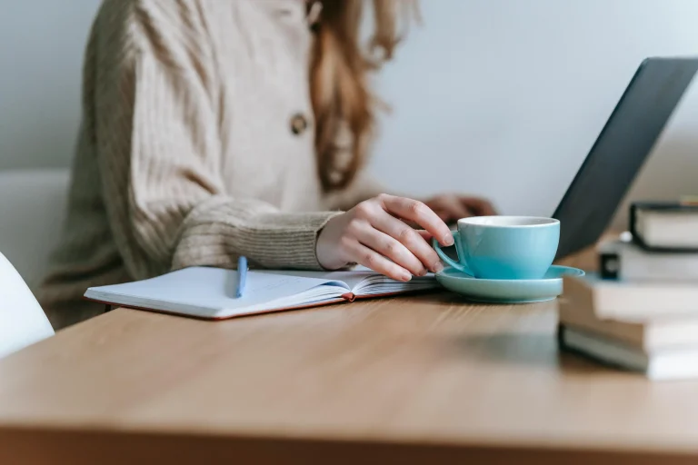 A parent sitting calmly with a laptop and a cup of coffee, practicing self-reflection and personal awareness as part of parental self-growth